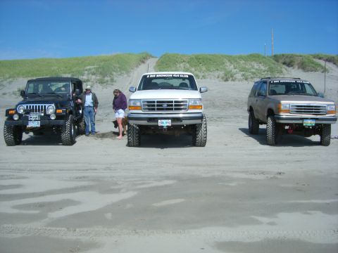 1994 Ford Explorer - A tan 1994 Ford Explorer is parked on a sandy beach alongside two other vehicles.