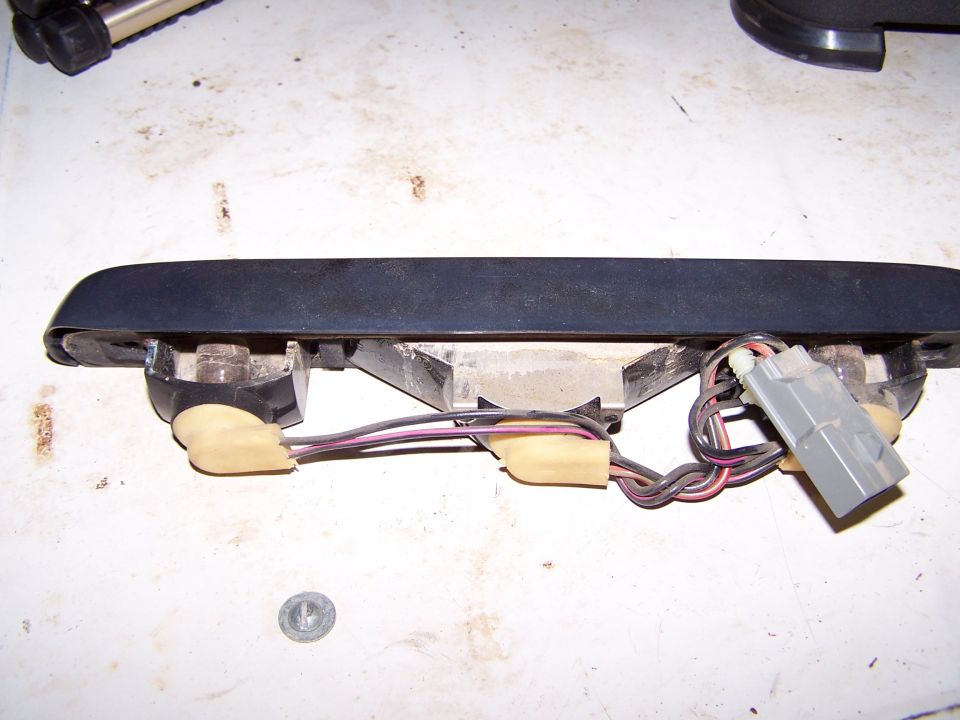 Black automotive light fixture with exposed wiring and a gray electrical connector