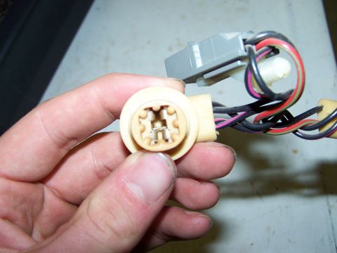 1995 Ford C-350 (Centurion Conversions) - A hand holds a beige wiring harness connector with a gray plug and multiple colored wires attached.