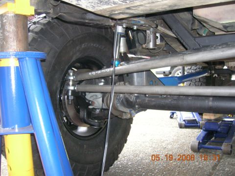 1996 Ford Bronco - Vehicle suspension and tire detail, with other vehicles and jacks in the background.