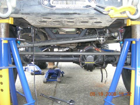 1996 Ford Bronco - The underside of a vehicle is supported by jack stands, revealing its complex mechanical components.