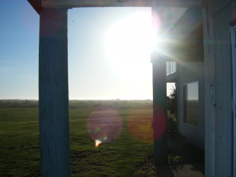 1994 Ford Explorer - A bright sun shines over a grassy field, viewed through porch columns.