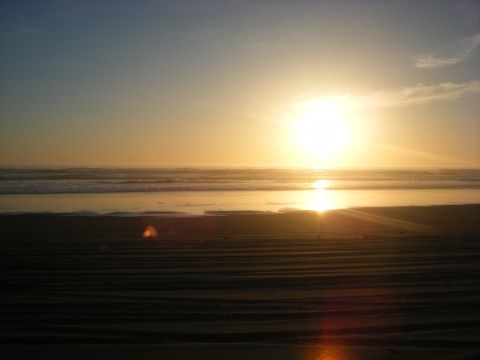 1994 Ford Explorer - Sunset over the ocean with waves and sand in the foreground.