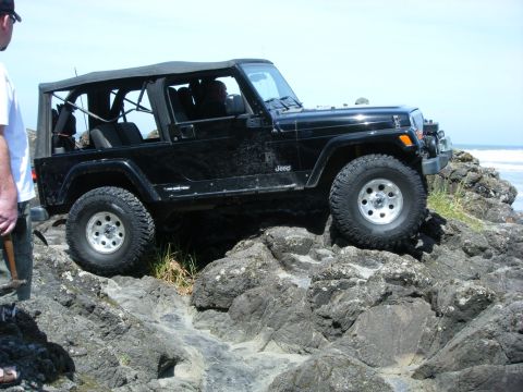 1994 Ford Explorer - A black Jeep Wrangler TJ navigates a rocky coastal path.