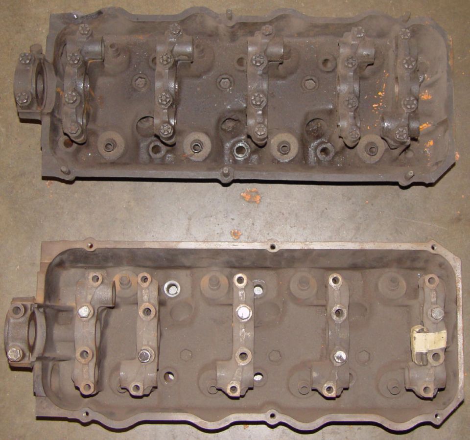 Two stripped overhead-cam cylinder heads with cam bearing caps installed, laid out on a shop floor