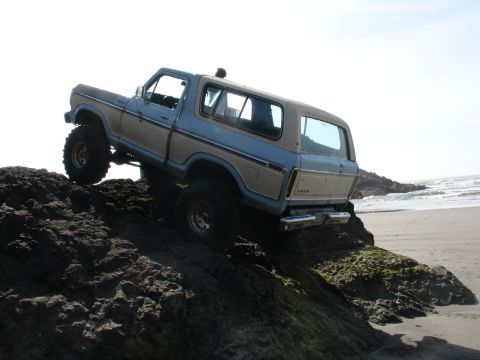 1978 Ford Bronco - Two-tone 1978 Ford Bronco navigates rocky terrain near the ocean.