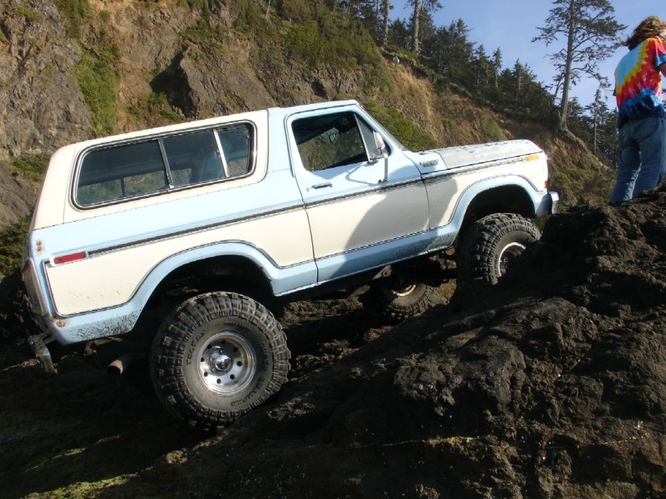 White and blue 1978 Ford Bronco climbing rocky terrain