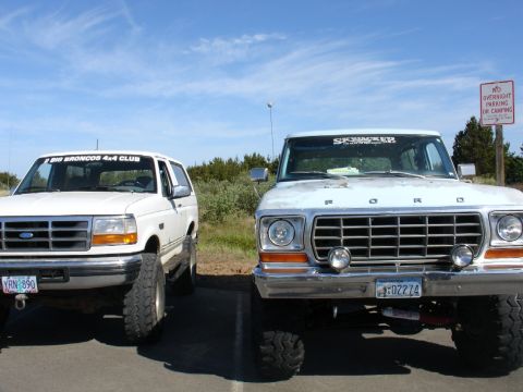 1978 Ford Bronco - Two Ford Broncos, one from the late 1970s and a more modern model, are parked side-by-side on a sunny day.