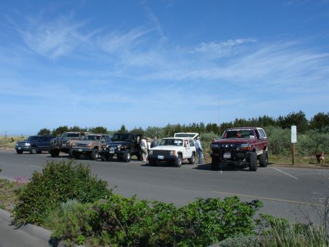 1978 Ford Bronco - Multiple off-road vehicles are parked together on a sunny day with a blue sky.