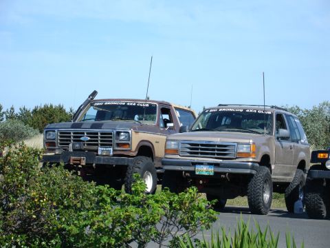 1978 Ford Bronco - Two off-road vehicles, a classic Bronco and a Ford Explorer, are parked together on a sunny day.