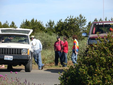 1978 Ford Bronco - A white Jeep Cherokee and a red SUV are parked on the side of a road with people standing around them.