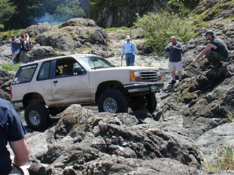 1978 Ford Bronco - An off-road SUV navigates a challenging rocky path with several onlookers observing the action.