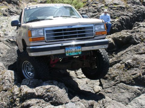 1978 Ford Bronco - A tan 1989 Ford Bronco navigates a rocky terrain, with its front-right tire significantly elevated.