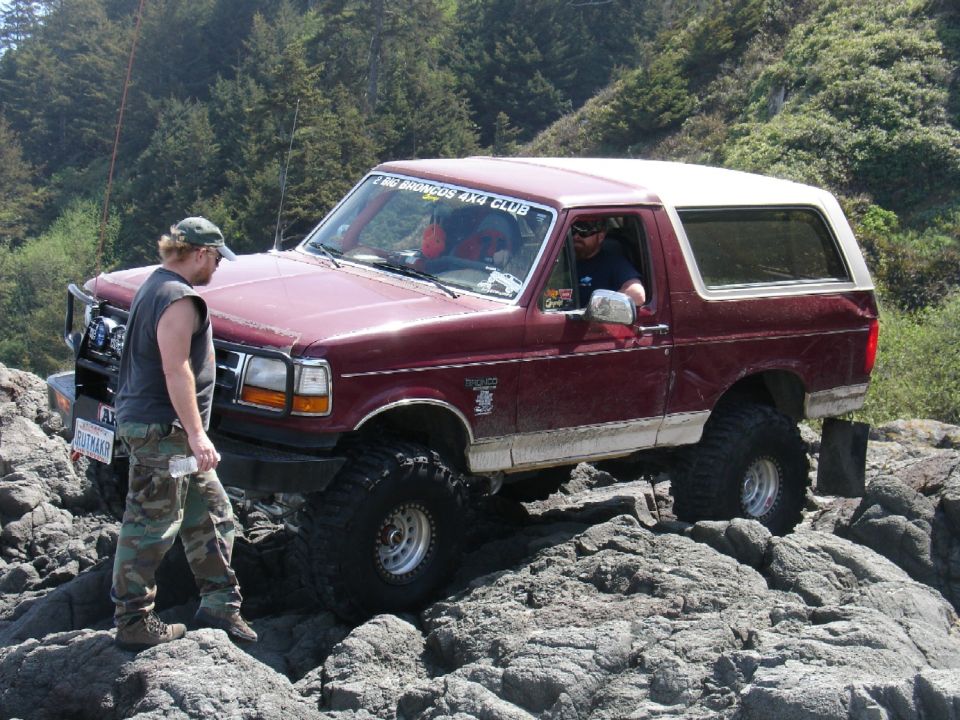 Maroon Ford Bronco with white top navigating rocks