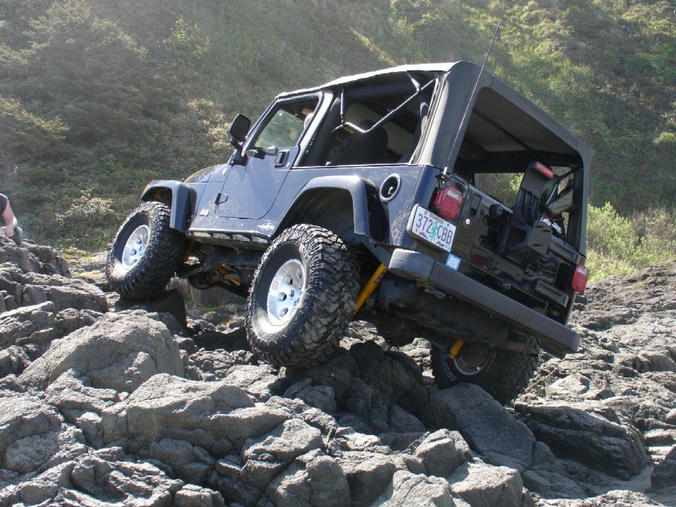 Dark blue Jeep Wrangler on rocky terrain, rear quarter view