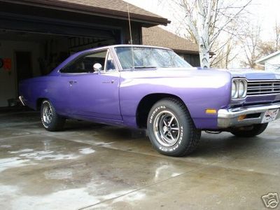 1999 Mercury Grand Marquis - A classic purple Plymouth Road Runner sits outside a garage.