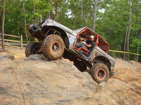 1978 Ford Bronco - A heavily modified off-road vehicle navigates a challenging rocky incline during an event.