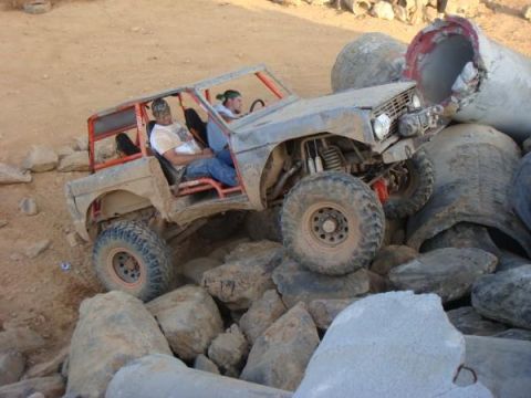 1978 Ford Bronco - A modified 1978 Ford Bronco is shown off-roading over large rocks and debris.