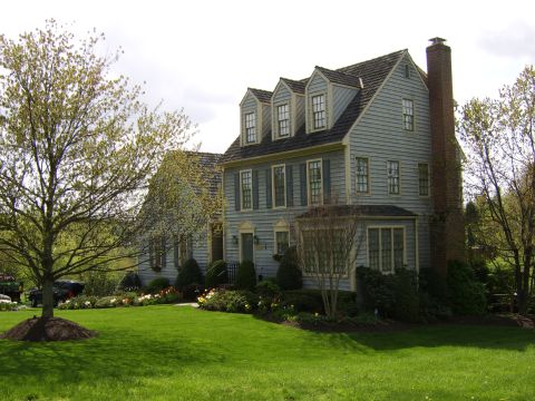 1996 Mercury Grand Marquis - A well-maintained suburban home is surrounded by lush green grass and blooming flowers under a cloudy sky.