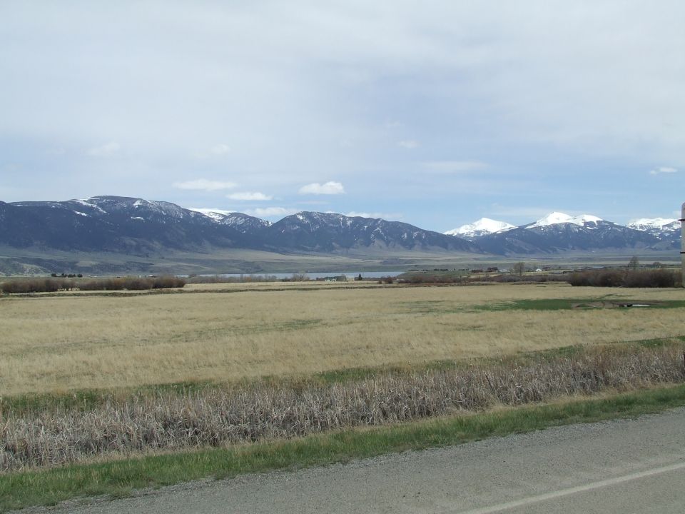 Wide view of a dry grass field with mountains in the background