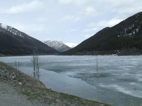 1979 Ford Bronco - A vast, icy lake is surrounded by dark, forested mountains under a cloudy sky.