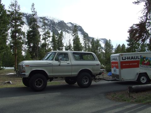 1979 Ford Bronco - Ford Bronco towing a U-Haul trailer on a trip with a mountain backdrop.