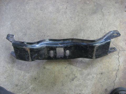 1978 Ford Mustang II - A black metal bracket, likely a component from a vehicle's undercarriage, is shown against a concrete surface.