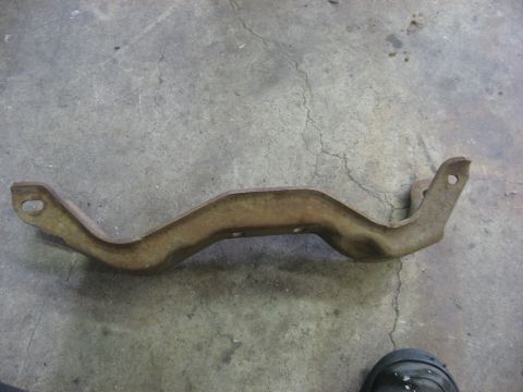 1978 Ford Mustang II - A single, rusted metal bracket lies on a concrete surface, likely a car part.