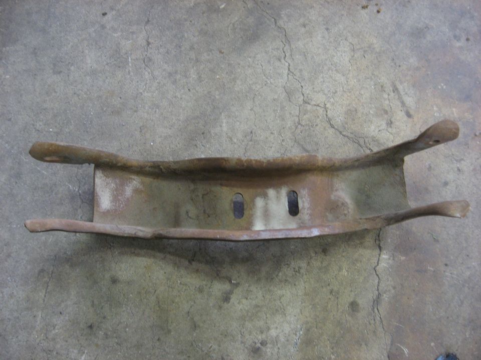 rusted metal bracket with two oblong holes in the center and two arms extending outwards