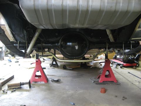 1978 Ford Mustang II - Underside view of a vehicle's rear axle and fuel tank, supported by red jack stands.