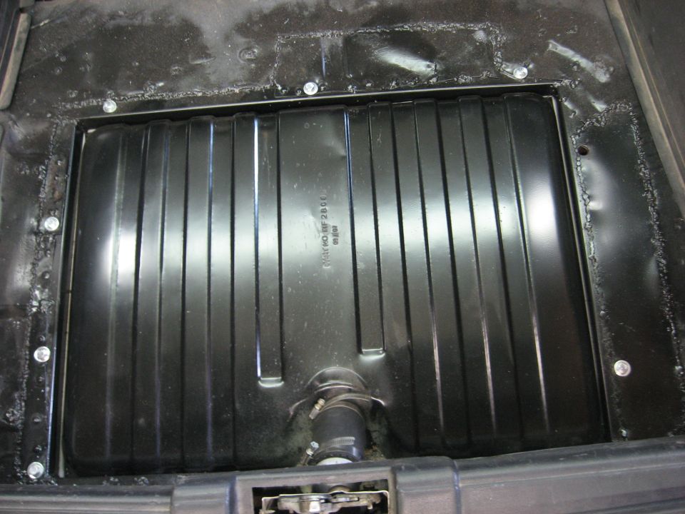 Black metal gas tank with ribbed surface and a hose attached