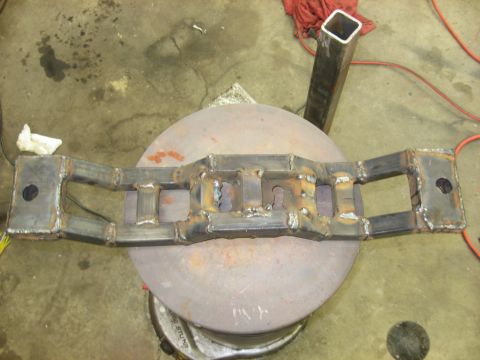1978 Ford Mustang II - A custom-fabricated metal component, likely for a vehicle, is shown in a workshop setting.