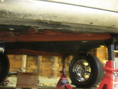 1978 Ford Mustang II - Underside view of a vehicle, focusing on the gas tank and exhaust system, supported by jack stands.