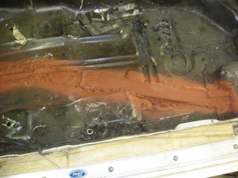 1978 Ford Mustang II - Undercarriage detail with rust and orange sealant, a Ford logo is visible on the lower trim.