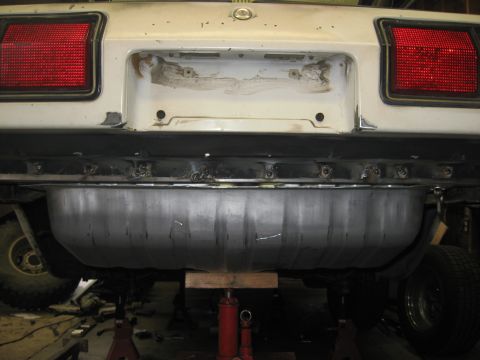 1978 Ford Mustang II - The rear of a white car shows a newly installed metal gas tank beneath the bumper and license plate area.
