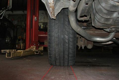 1985 Ford LTD Crown Victoria - A close-up view of a vehicle's tire and undercarriage, with a car lift visible in the background.