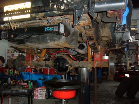 1994 Ford Bronco - The underside of a vehicle, showing the suspension, fuel tank, and a CURT hitch, is displayed while on a lift.