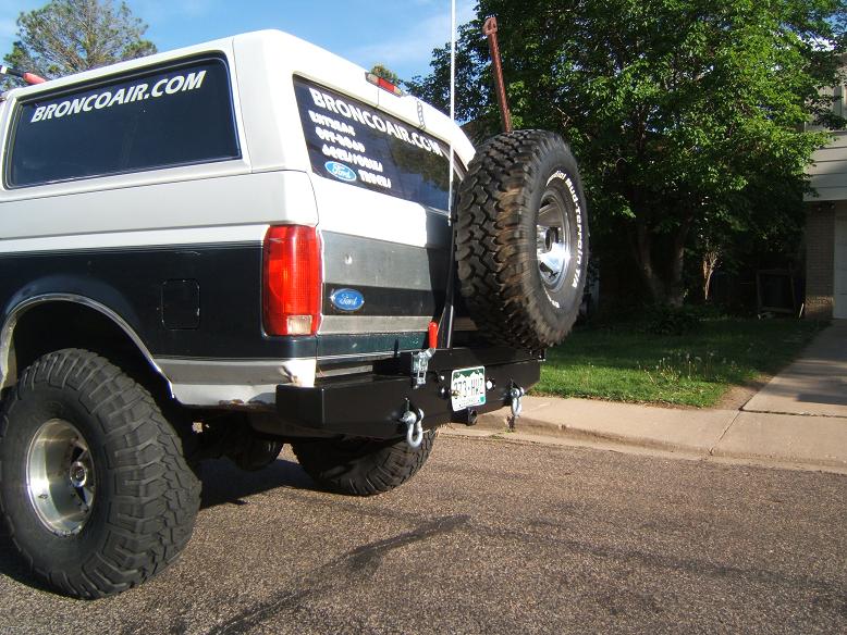 White and black Ford Bronco with a rear-mounted spare tire and aftermarket bumper