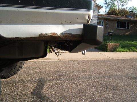 1993 Ford Bronco - Close-up of a rusted rear bumper corner and tow hitch, showing wear and tear.