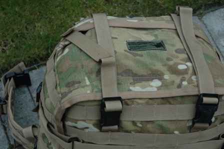 1991 Ford Bronco - A camouflage backpack with multiple straps and buckles is shown outdoors on a paved surface with grass in the background.