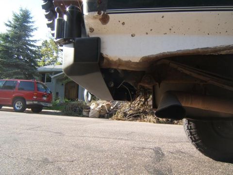 1993 Ford Bronco - The underside of a vehicle shows a bumper bracket and exhaust system, with a red SUV in the background.