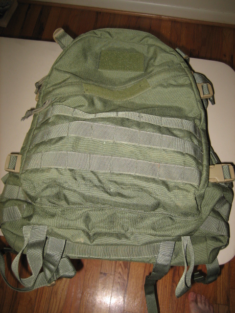 1991 Ford Bronco - A green tactical backpack with multiple straps and buckles is shown against a wooden floor background.