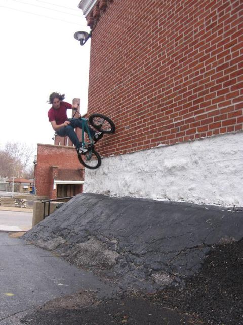 1988 Ford Bronco - A BMX rider attempts a trick on a ramp next to a brick building.