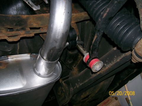 1995 Mercury Grand Marquis - Underbody view of a newly installed bright aluminized muffler with its inlet pipe curving up over a rusty leaf spring and frame rail. To th…