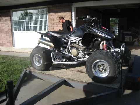 1981 Ford Bronco - A black ATV is parked on a trailer outside a garage.