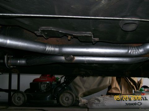 1995 Mercury Grand Marquis - Underside view of dual exhaust pipes, with a lawnmower in the background.