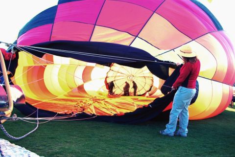 1995 Ford Bronco - A hot air balloon is being laid out on the grass, with people inside and a woman holding ropes.
