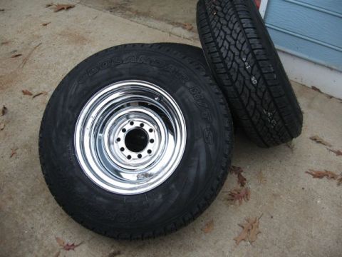 1966 Ford F-100 - A pair of tires and wheels are shown resting on a concrete surface with scattered leaves.