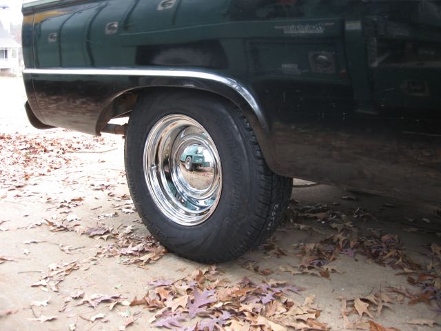Low view of chrome smoothie wheel and wide tire on the rear of a black Ford pickup