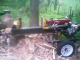 1946 Ford F1 - A log splitter is shown with a hydraulic cylinder and an engine, surrounded by split wood.
